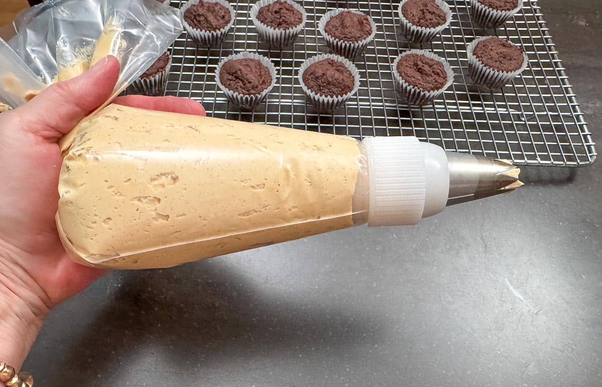 Piping bag filled with peanut butter frosting with tip.