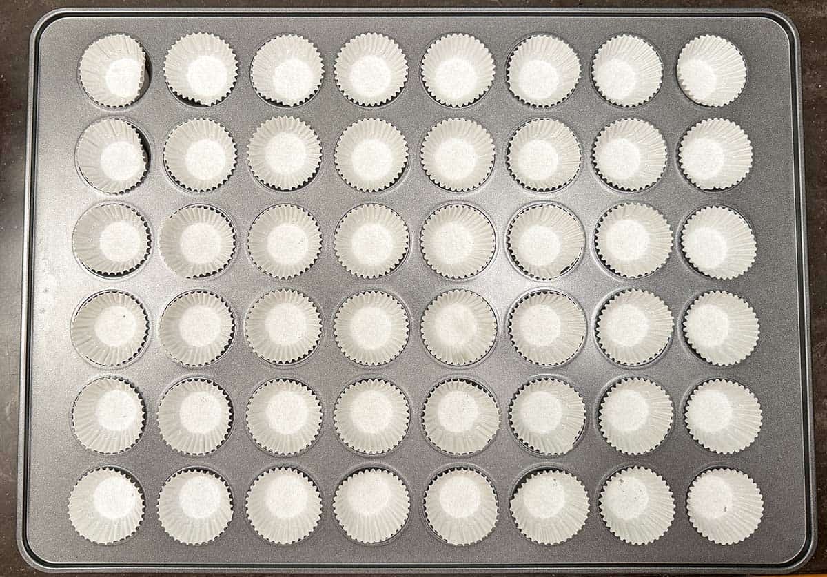 A 48 cup mini muffin pan with mini wrapper in each cup.