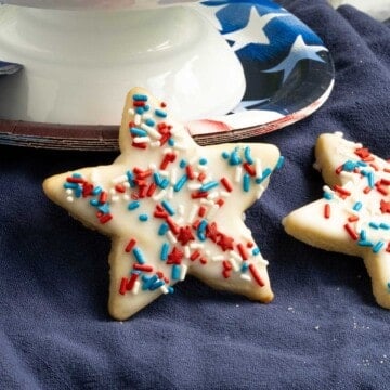 Honey almond glazed cookies leaning against a plate that is for 4th of July.