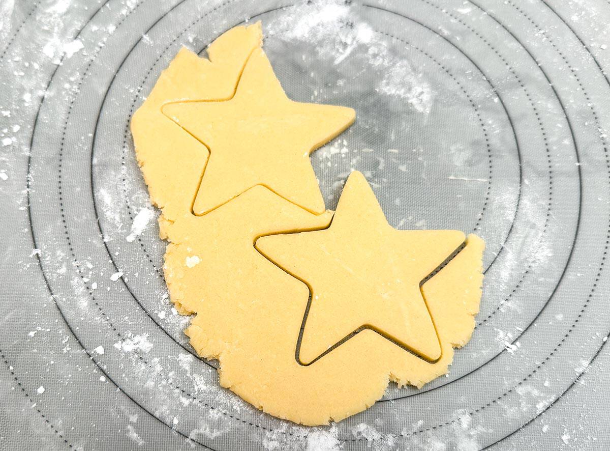 Cutout stars of cookie dough on a pastry mat.