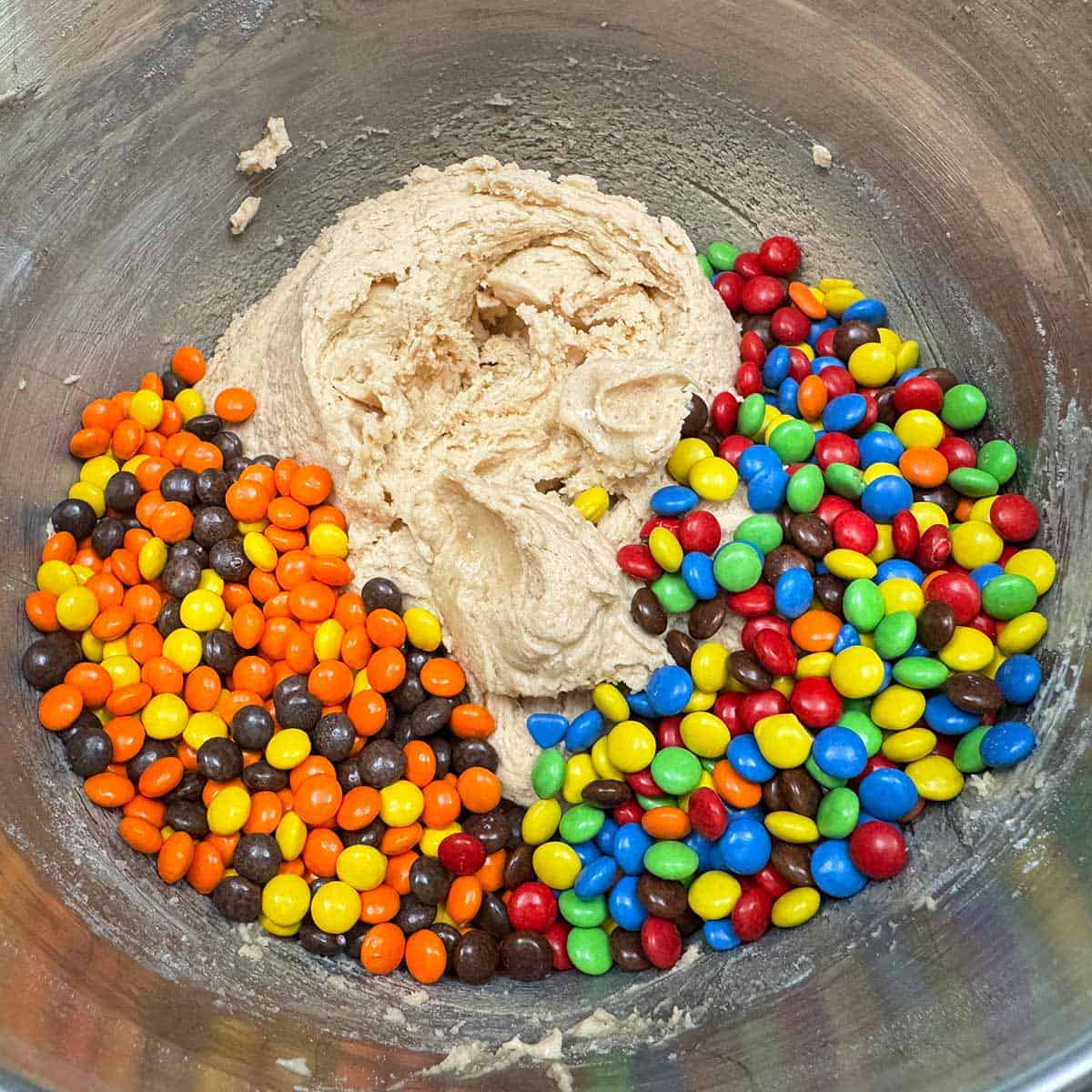 Adding the Reese's pieces and the M&M mini candy to the cookie dough.