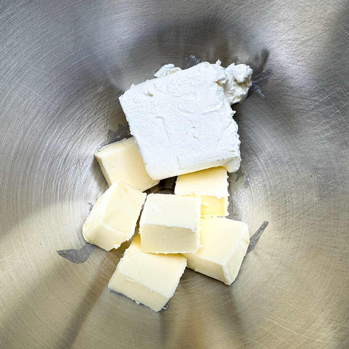 Cubed butter and a half of block of cream cheese in a mixer bowl.