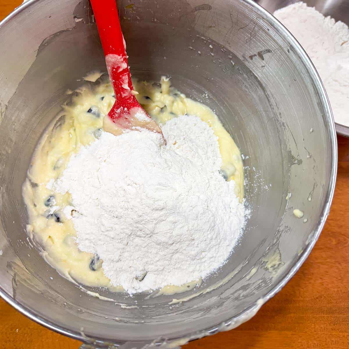 Adding the flour mixture to the wet cookie dough with a spatula.