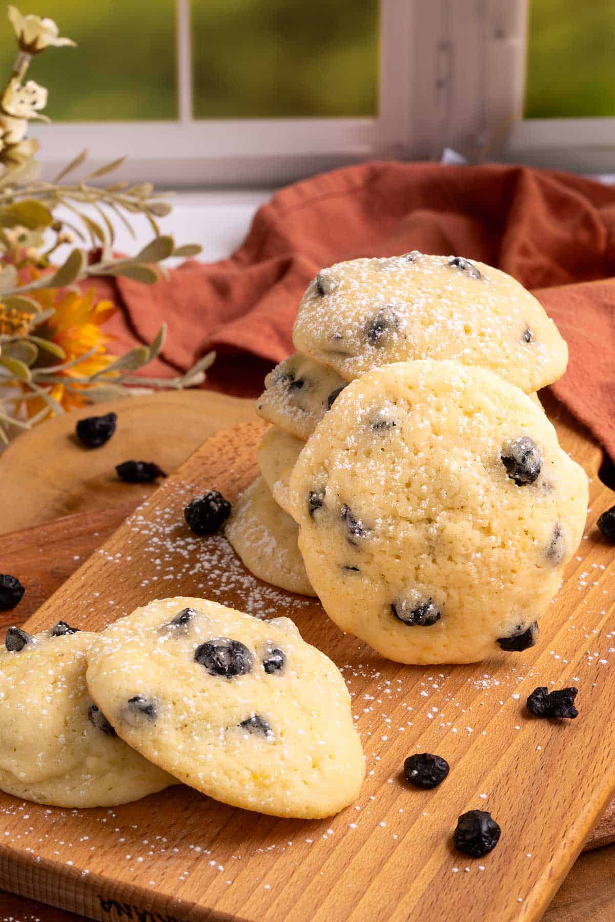 Blueberry Lemon with Mascarpone Cookies are stacked on a wooden board with powdered sugar sprinkled on top.