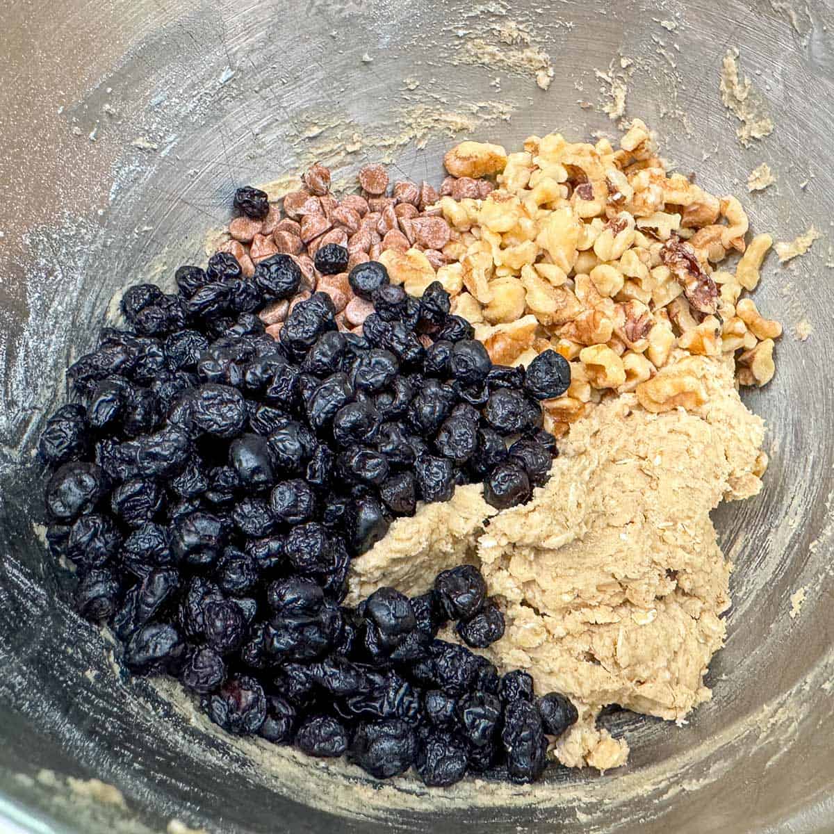 Adding blueberries, walnuts, and cinnamon chips to the cookie dough.