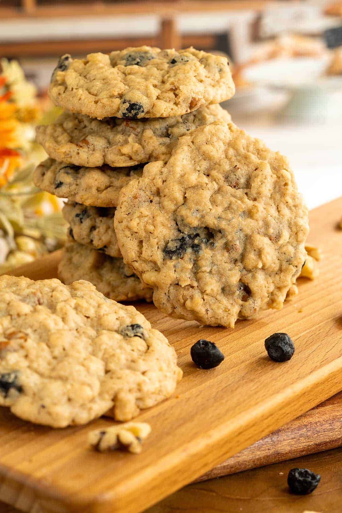 Blueberry cinnamon oatmeal cookies stacked with one leaning against the stack to show the front view on a cutting board.