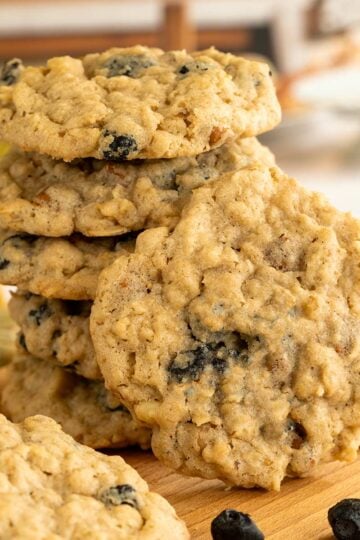 Blueberry cinnamon oatmeal cookies stacked with one leaning against the stack to show the front view.
