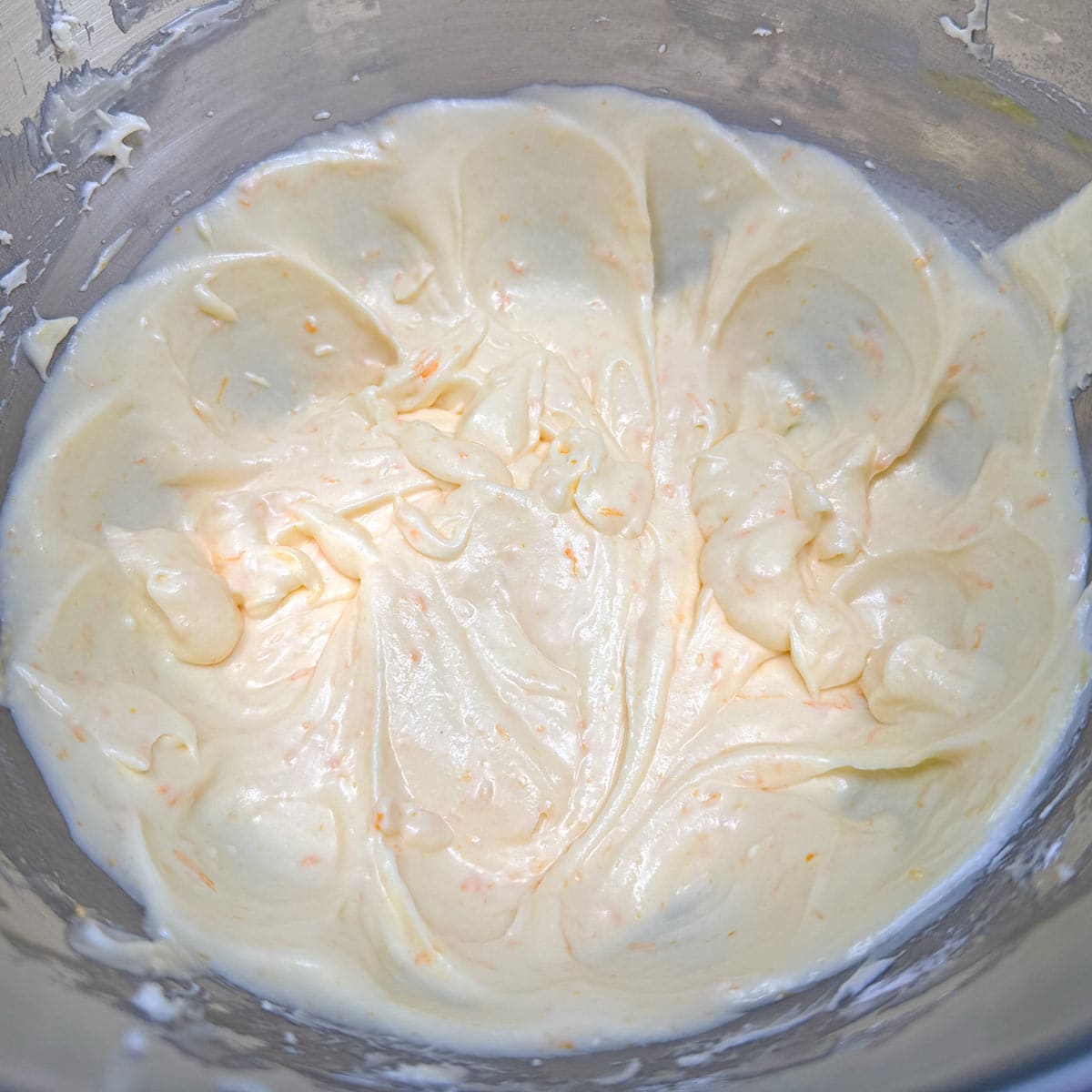 The cookie wet ingredients have all be mixed in with a faint orange color and pieces of orange zest throughout.