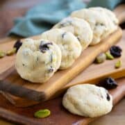 Cherry Orange with Pistachio Cookies lined up on a wooden board. The cherries and orange zest show through.