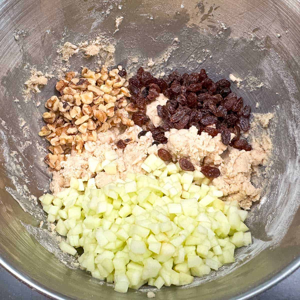 Adding the cut up apple pieces, walnuts and the raisins to the cookie dough.