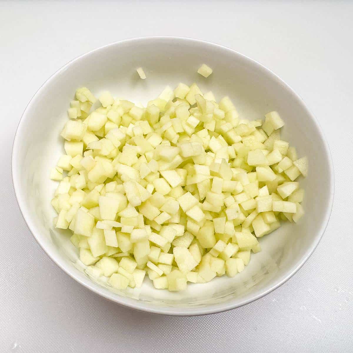 All the diced apple pieces in a bowl from one granny smith apple.