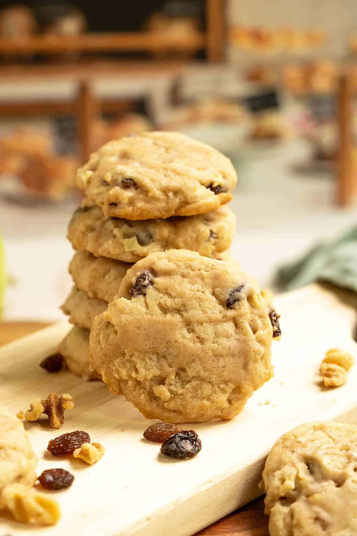 The front view of one of the cookies leaning against a stack of Apple Cider cookies on a cutting board.