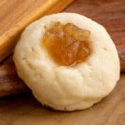 A thumbprint cookie with pear filling on a wooden board.