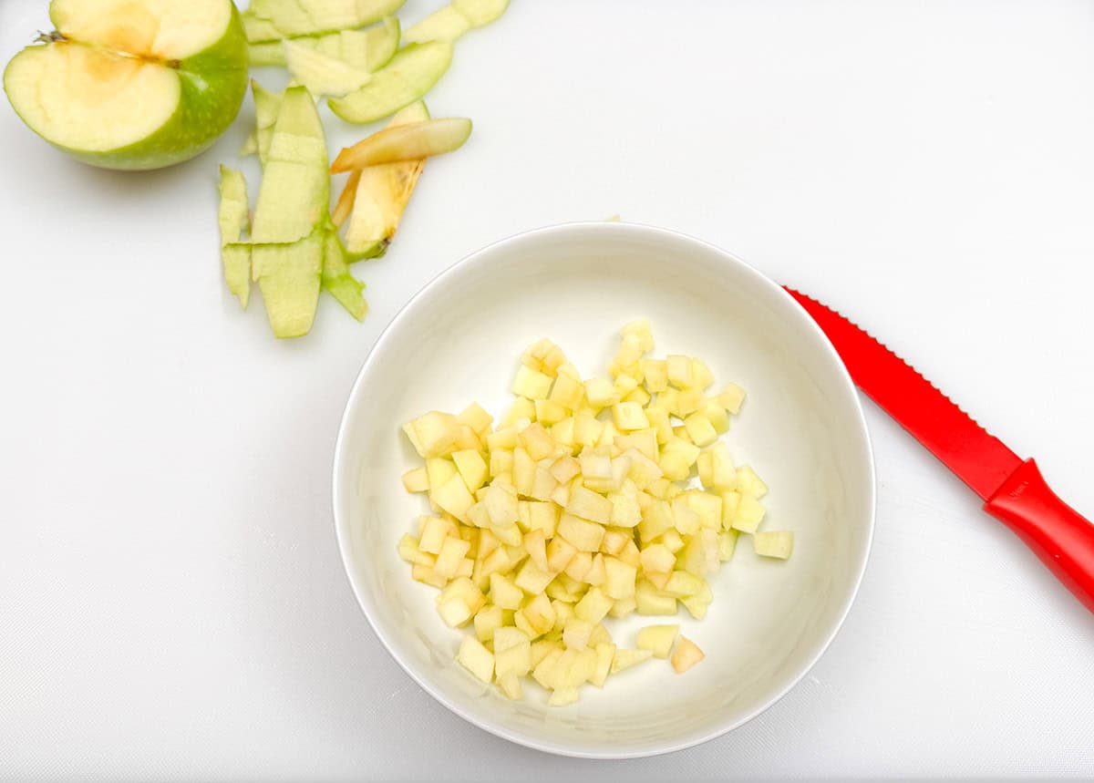 Diced apple in a bowl on a cutting board.