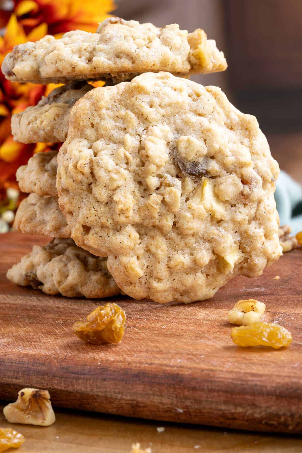 Apple oatmeal raisin cookies with walnuts front view of a whole finished cookie with pieces of walnuts laying around.
