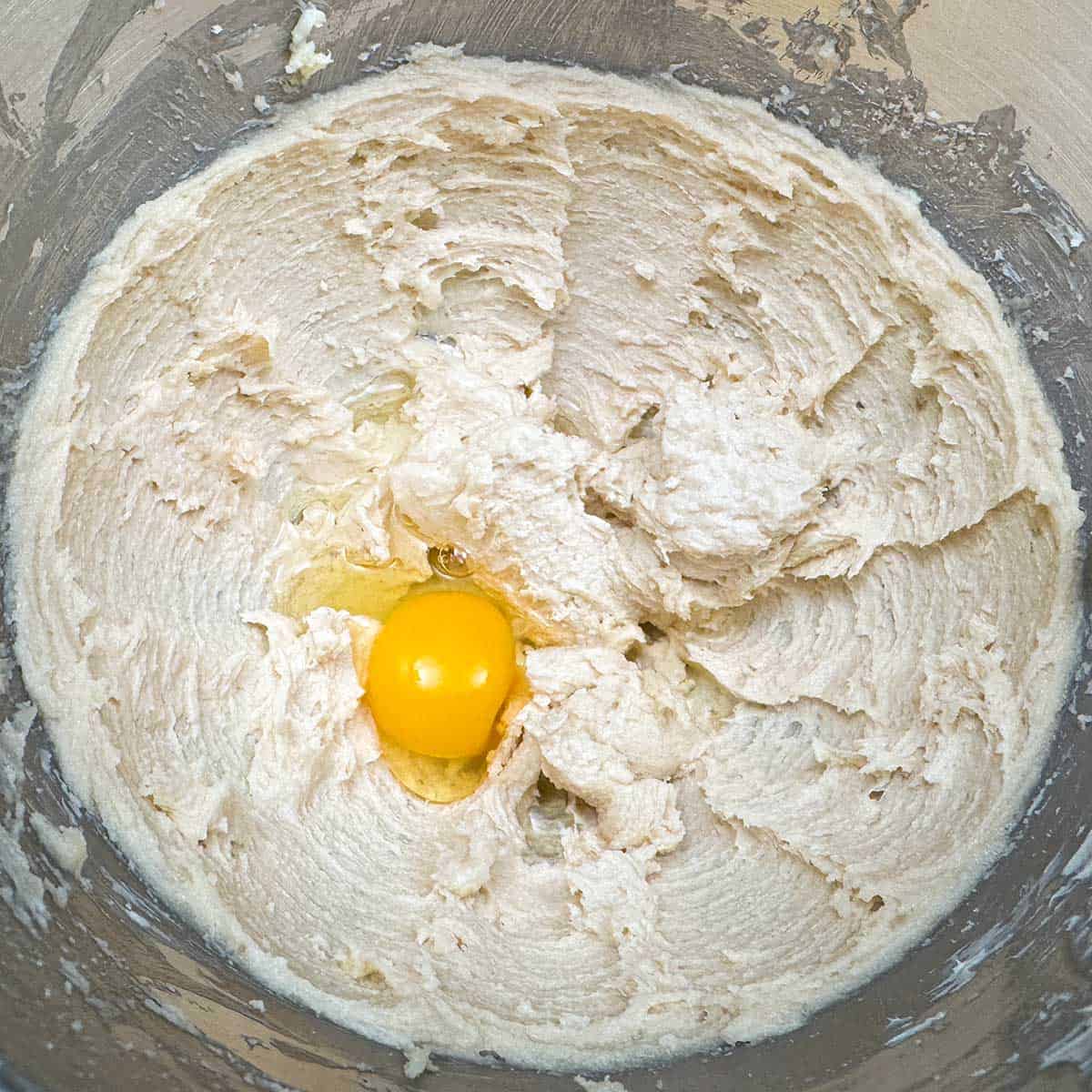 Adding an egg and apple juice to the butter-sugar mixture in mixing bowl.