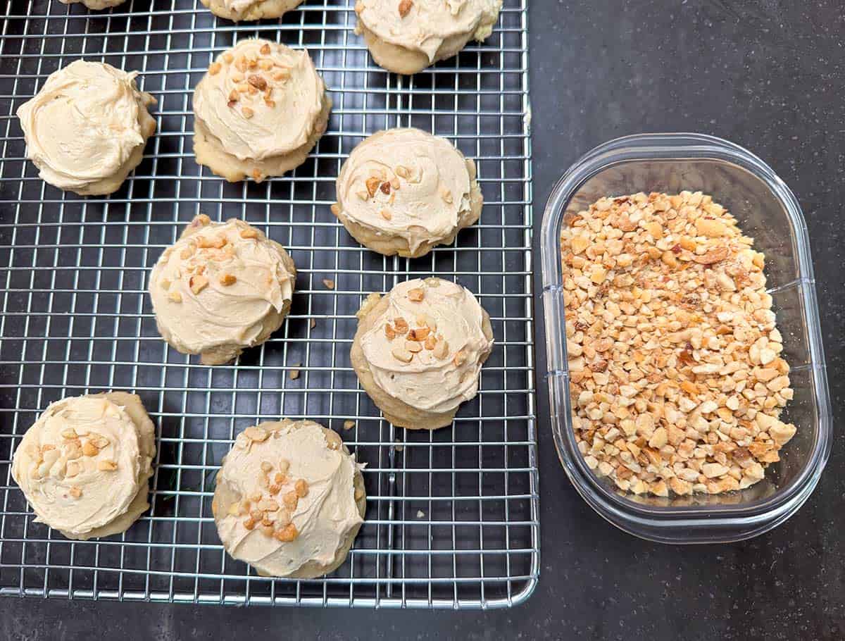 Cookie that have been frosted and chopped peanuts sprinkled on the tops of each cookie.