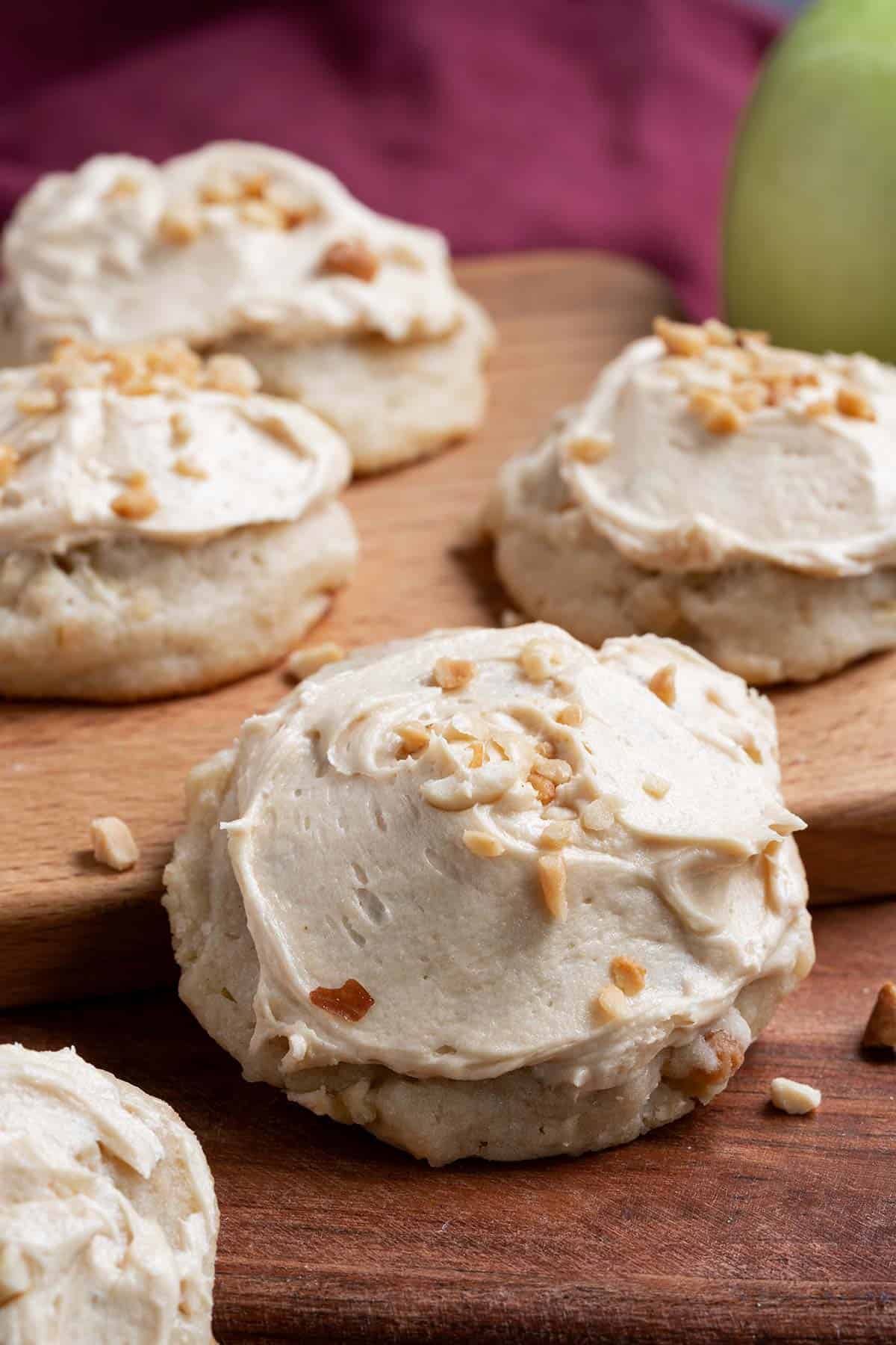 Caramel Apple Cookies with Peanuts sitting on a wooden cutting board surrounded by more cookies.