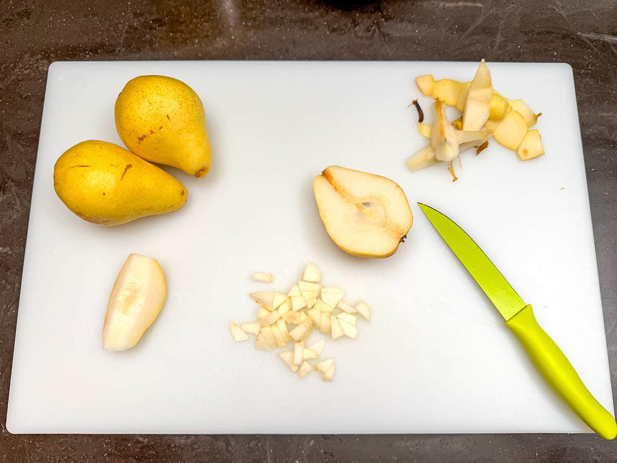Cutting the pears into small pieces on a cutting board.