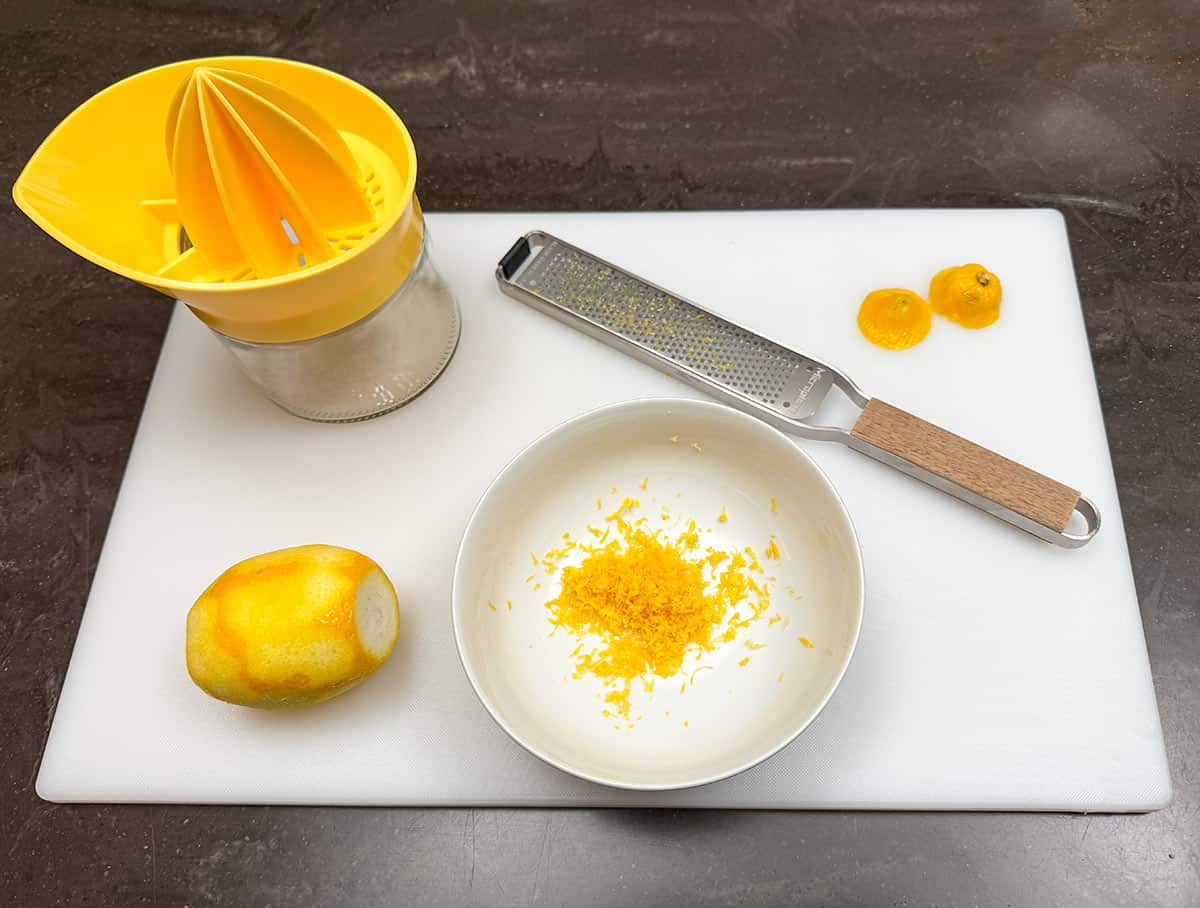 Zesting and juicing a lemon on a cutting board.