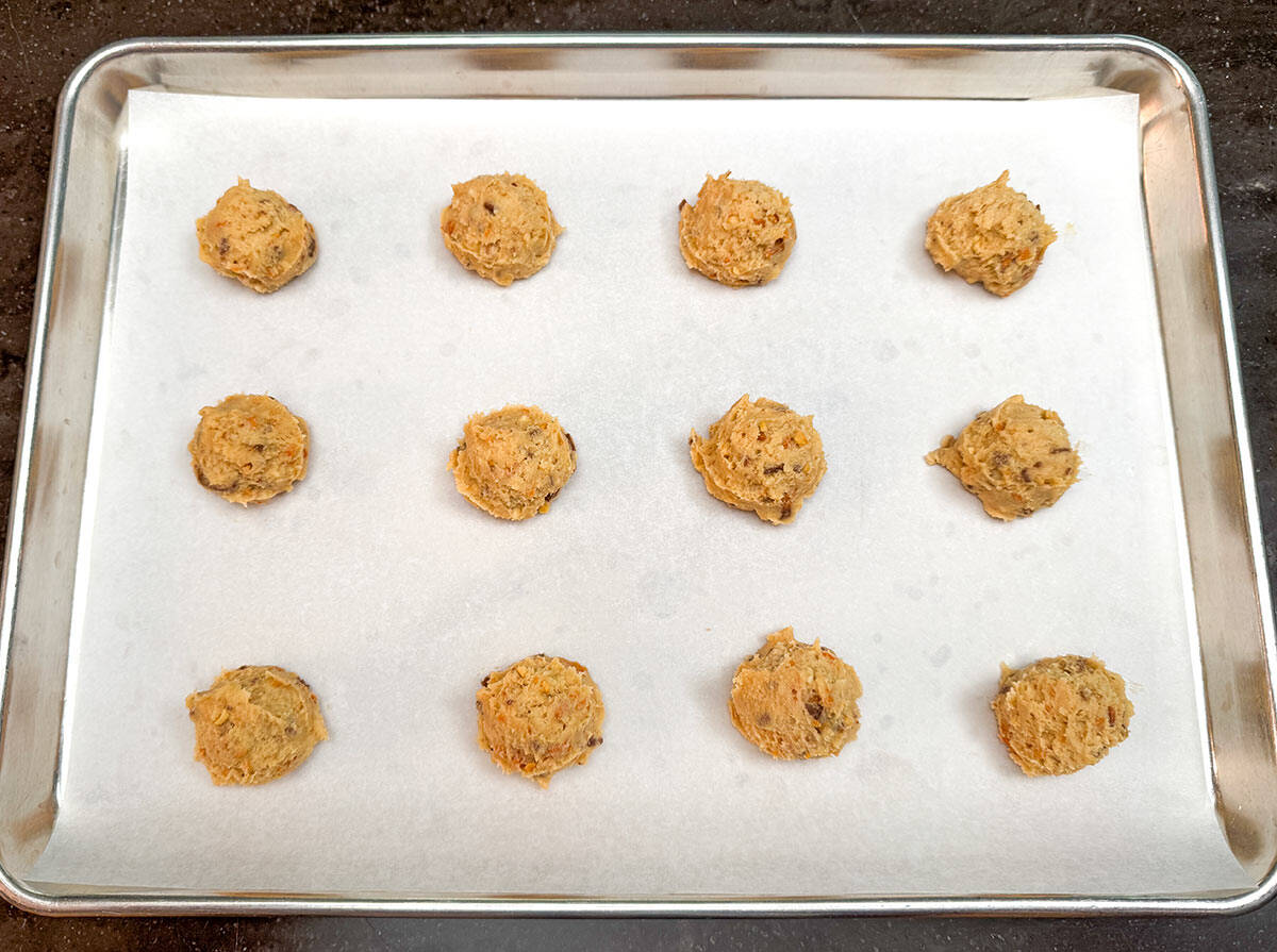 Twelve cookie dough mounds with roasted peanuts mixed in are ready for the oven.