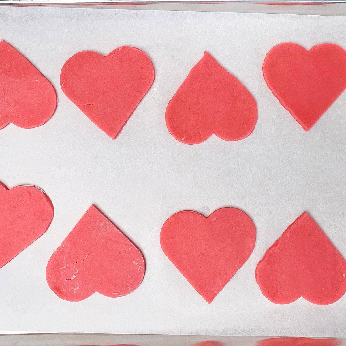 Heart shaped cookies on a parchment lined sheet pan.