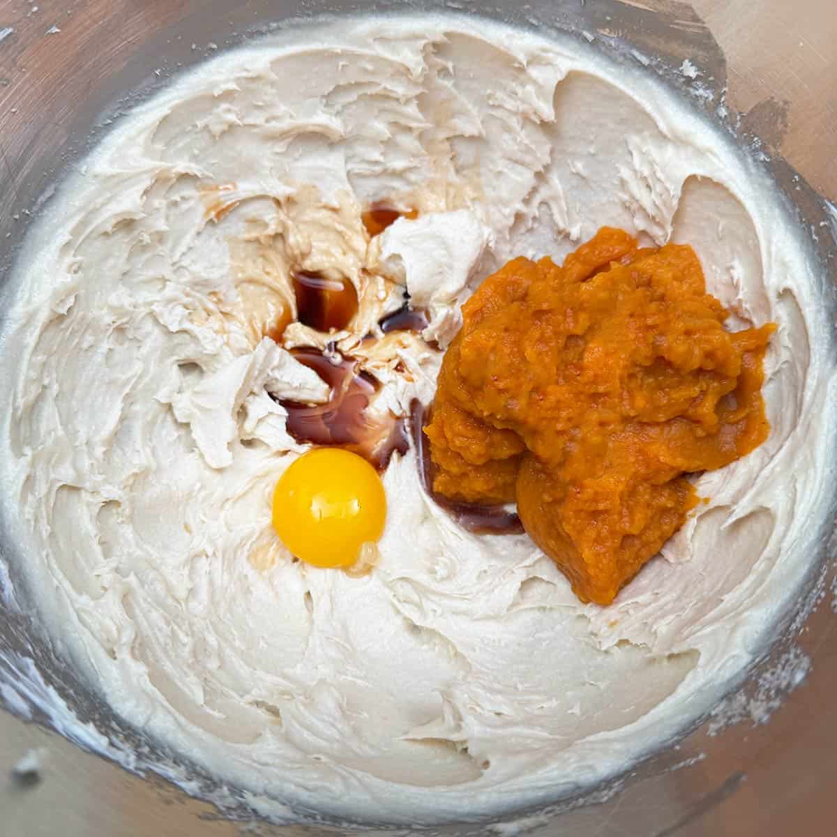 Adding an egg, vanilla extract and pumpkin to the sugar butter cookie dough.
