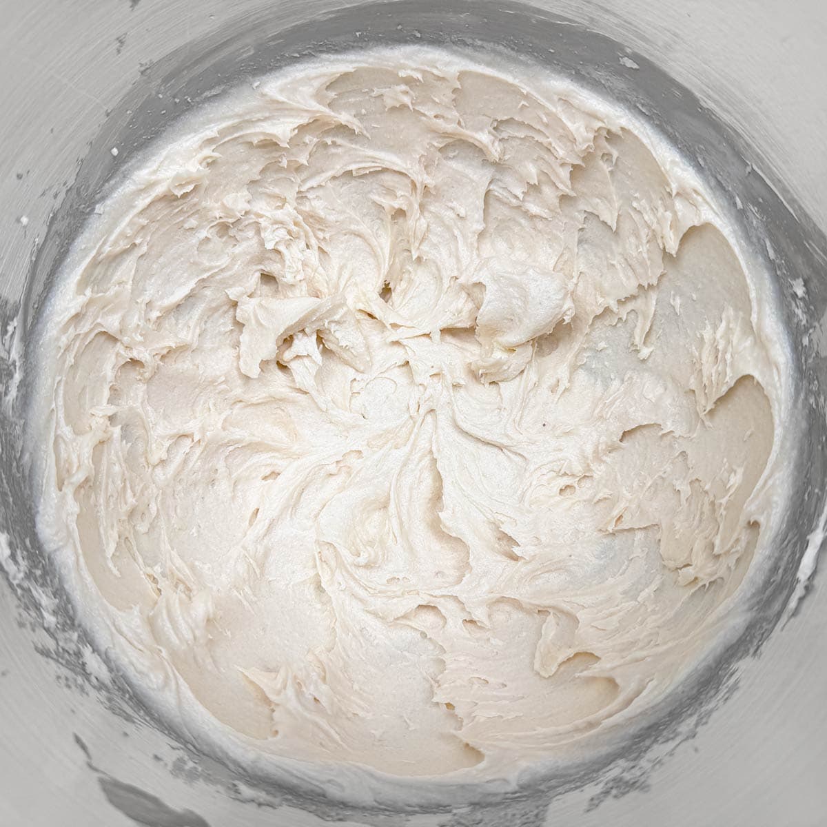Butter sugars and cream cheese all mixed together in a mixer bowl.