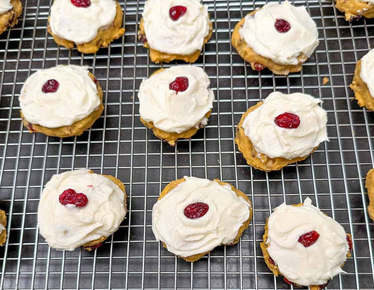 Finished cookies with icing and a cranberry right in the middle on top of the icing.