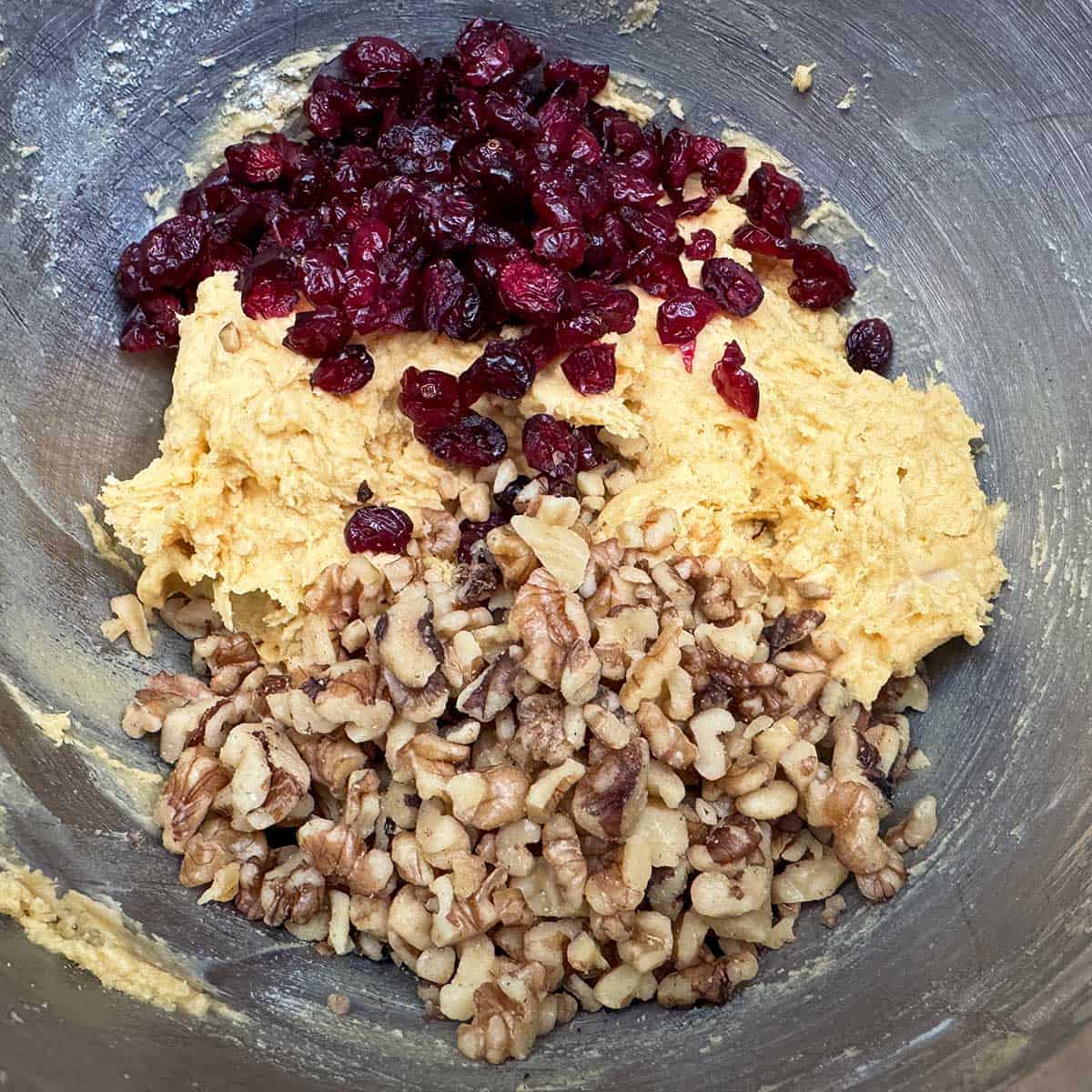 Adding the chopped walnuts and the dried cranberries to the cookie dough.