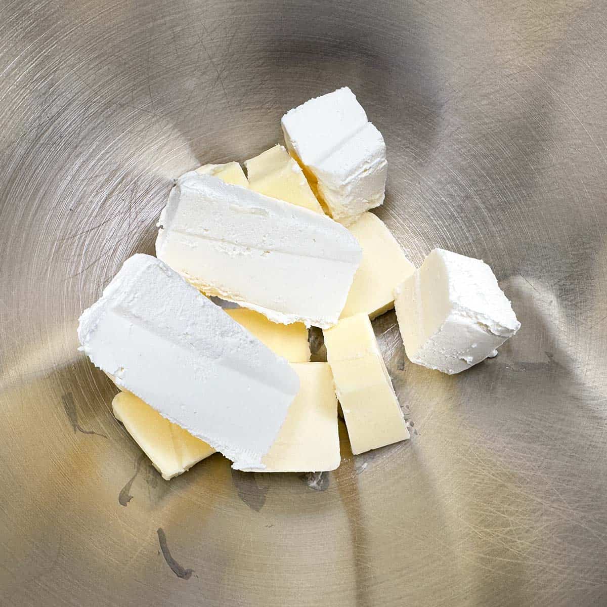 Cubed butter and blocks of cream cheese in the mixer bowl for the cookie dough.