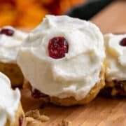 Pumpkin Cranberry cookies with Cream Cheese Icing closeup on a cutting board.