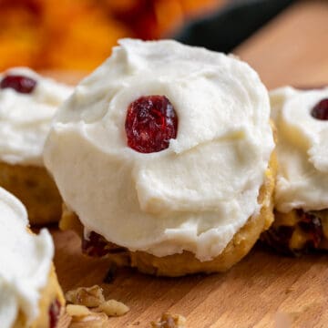 Pumpkin Cranberry cookies with Cream Cheese Icing closeup on a cutting board.