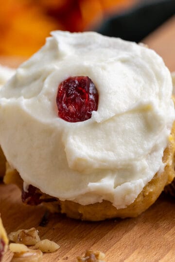 Pumpkin Cranberry cookies with Cream Cheese Icing closeup on a cutting board.