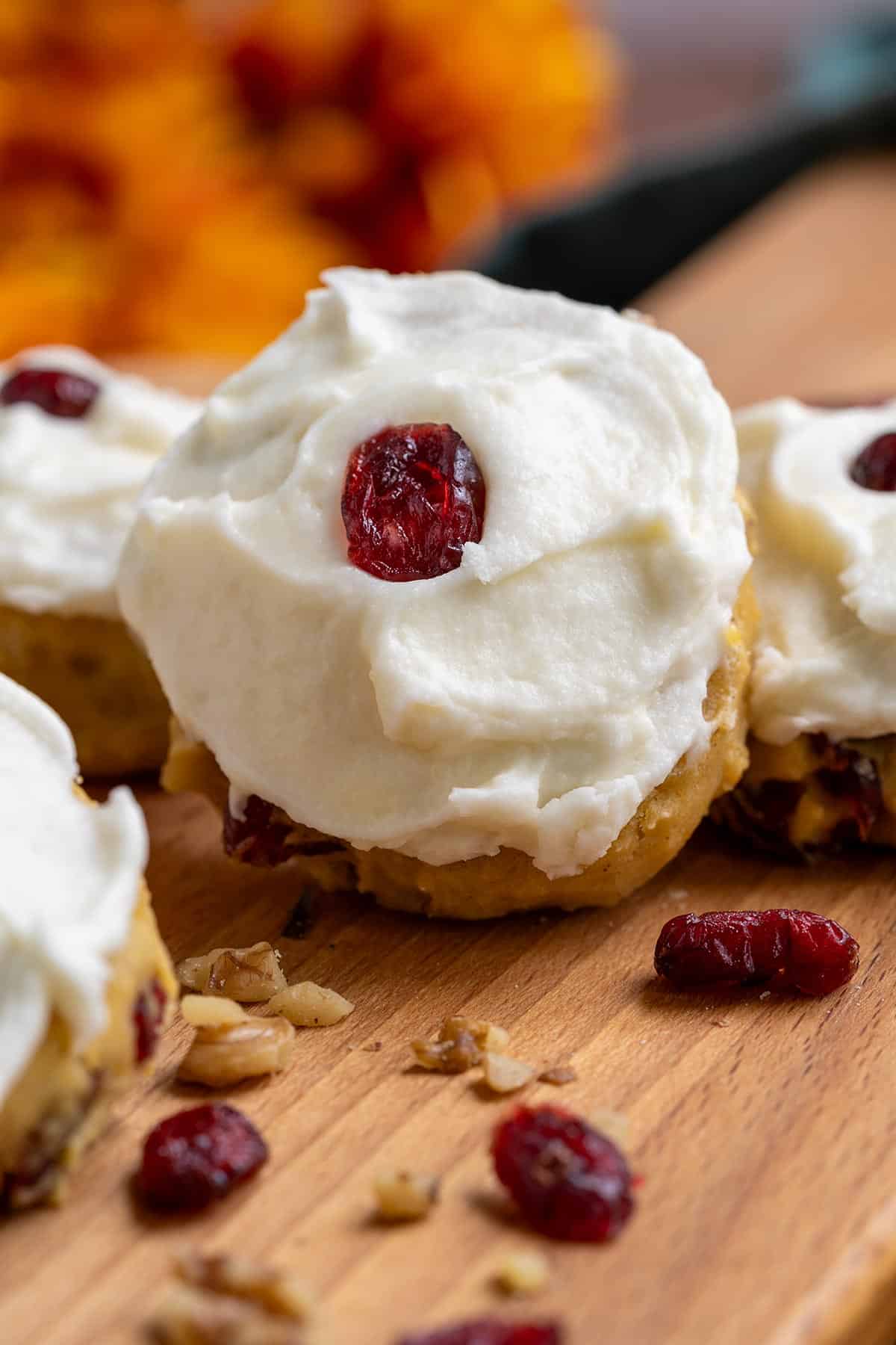 Pumpkin Cranberry cookies with Cream Cheese Icing feature on a cutting board.