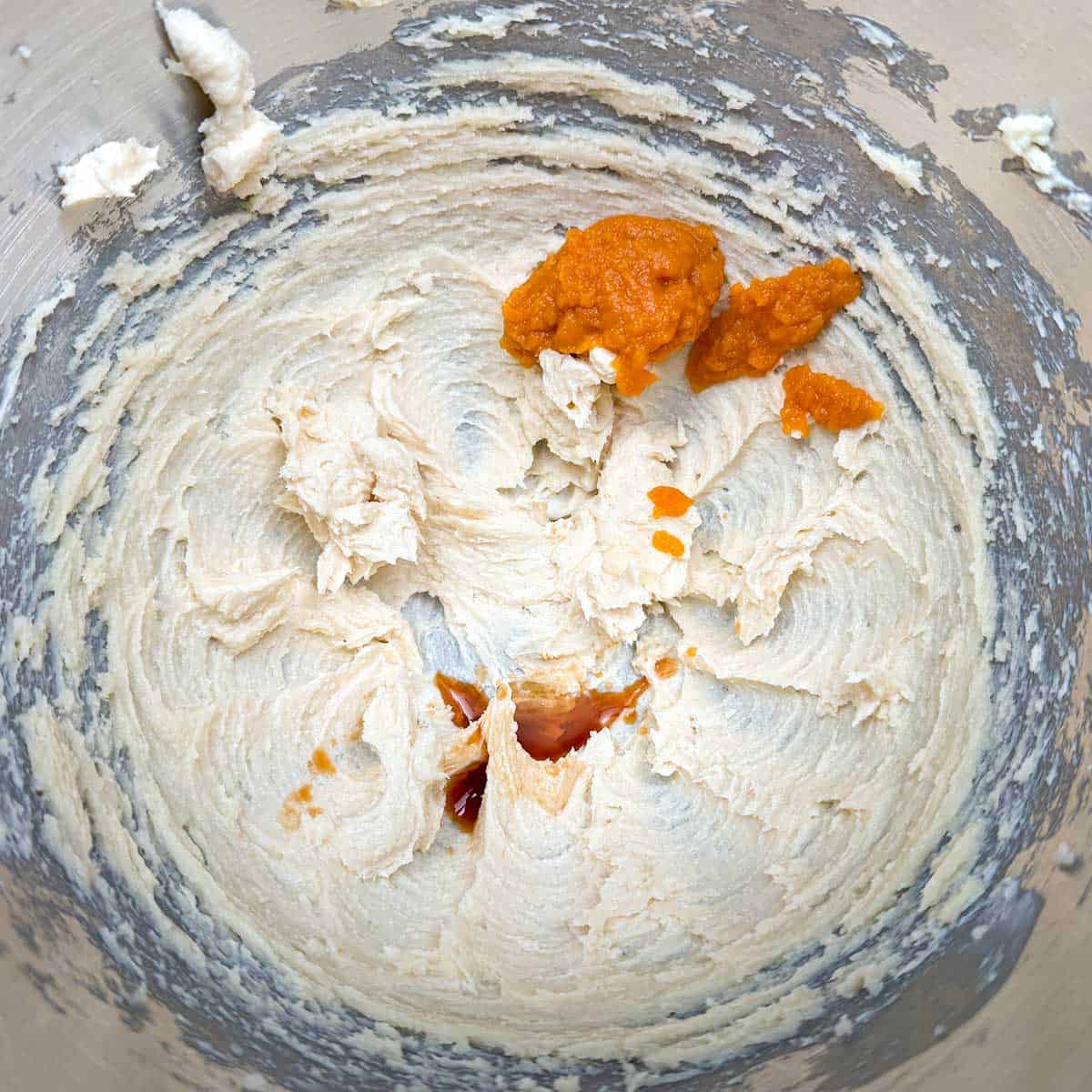 Adding the vanilla extract and pumpkin puree to the butter-sugar mixture.