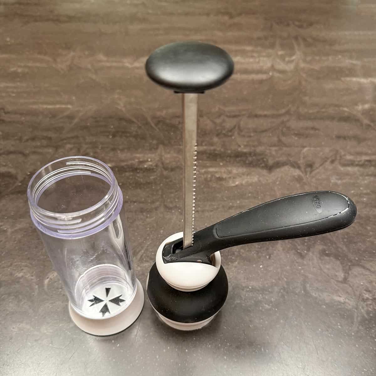 The cookie press with the plunger pulled up and screwed off the center cylinder.
