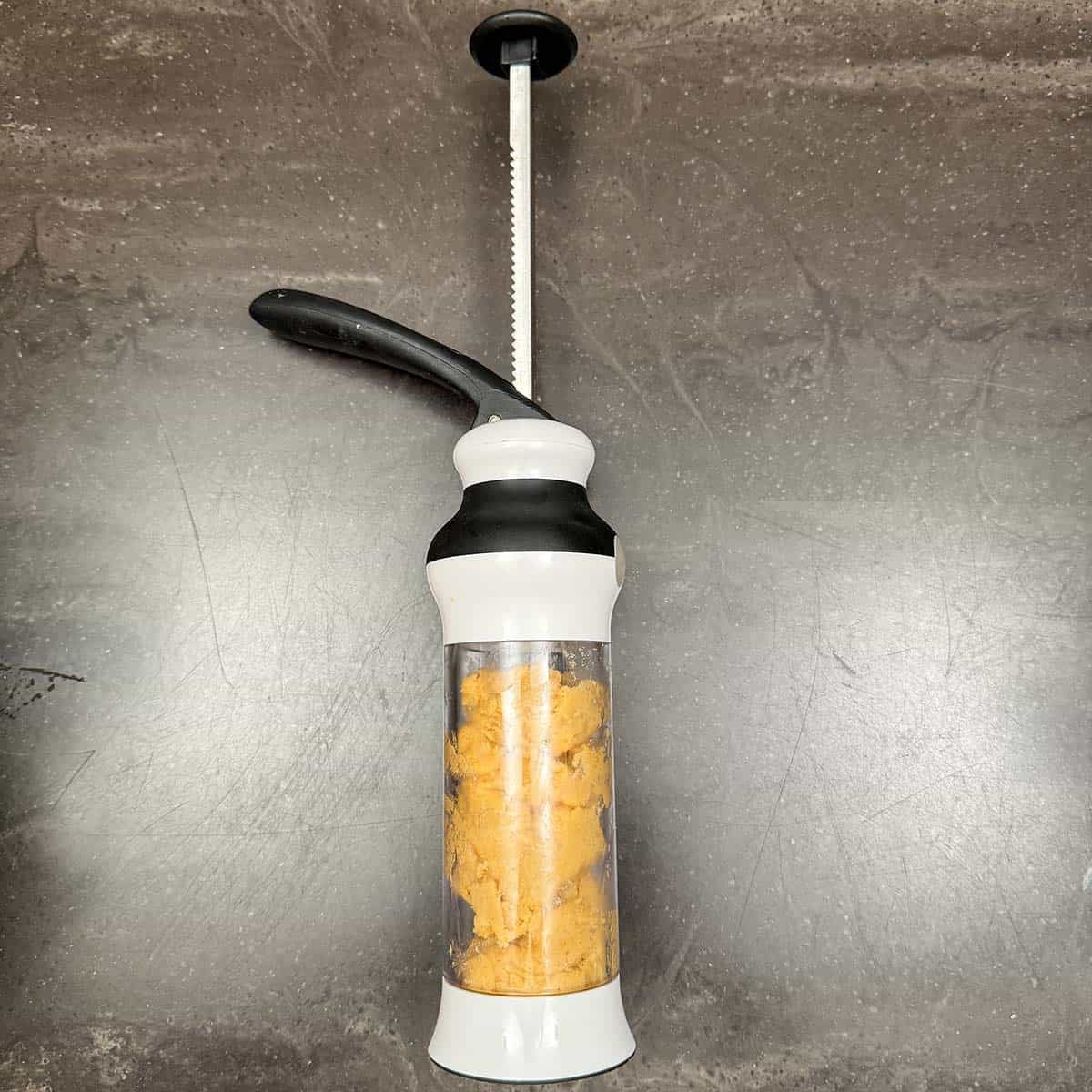 Loosely filled cookie press before pressing the dough down the cylinder.