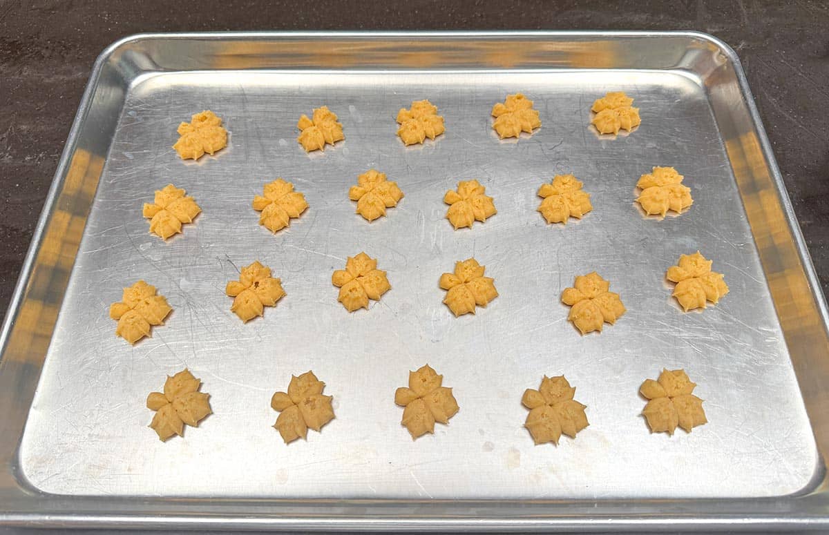 Pressed out cookies on a sheet pan ready for the oven.