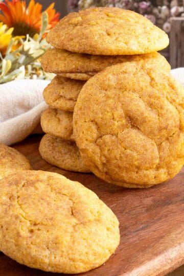 Pumpkin spice snickerdoodle cookies stacked on a wooden board.